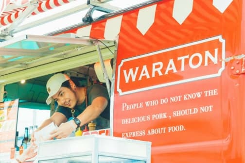 G・ファームのキッチンカーで、笑顔でお客様に商品を渡す男性スタッフ