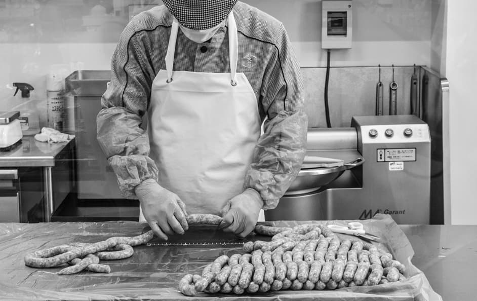 加工場で職人が一本ずつ丁寧にソーセージをひねって成形する様子