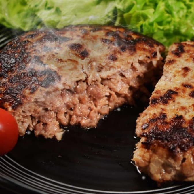 鉄板でジューシーに焼き上げられ、肉汁が溢れ出るカットされたハンバーグステーキ