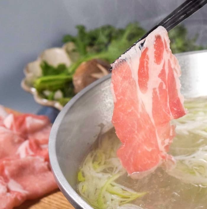 箸で持ち上げられた薄切りの豚しゃぶしゃぶ肉