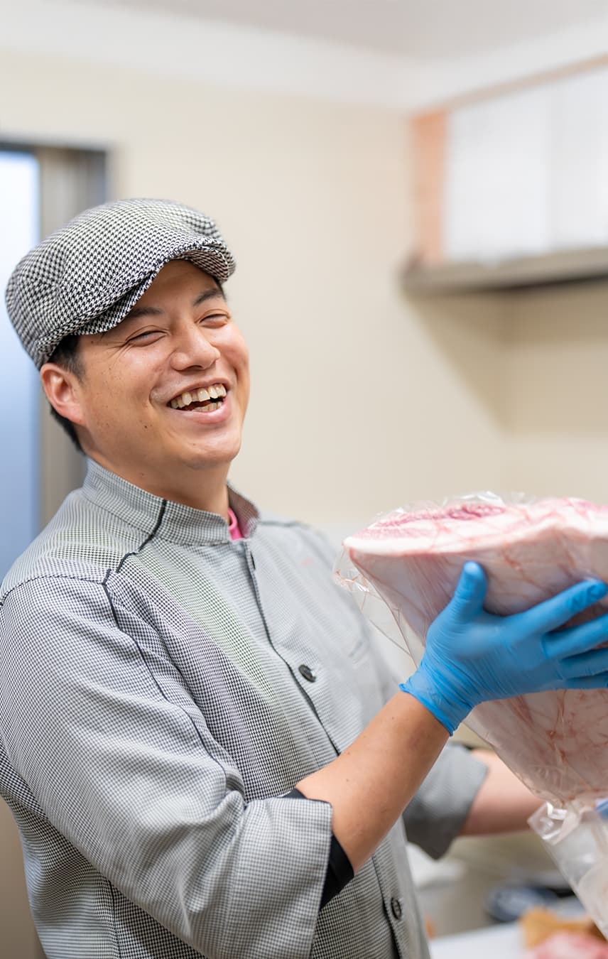 パッケージされた豚肉を笑顔で掲げるスタッフ